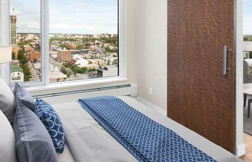 bedroom with floor to ceiling window, a bed and a sliding door