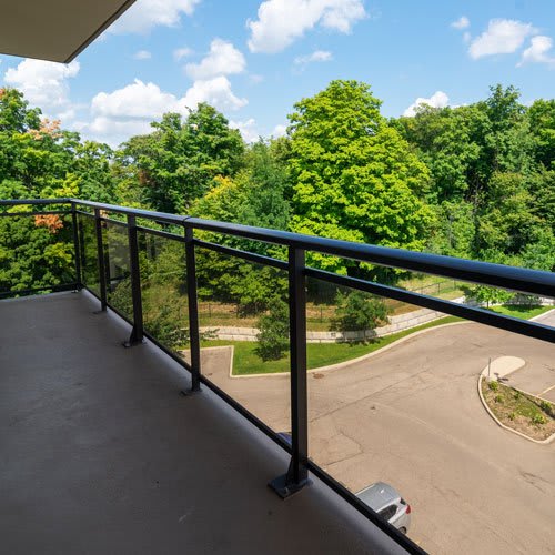 Large balcony overlooking trees and parking area.