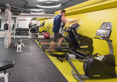 fitness room with exercise equipment and a person running on a treadmill