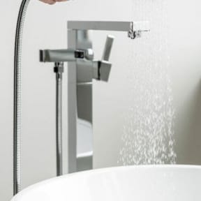 a bathtub with a shower and a hand holding a shower head at Altaire, Virginia, 22202