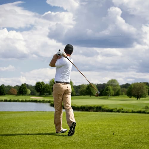 a man swinging a golf club on a golf course at Harbor Heights 55+ Community, Olympia, 98501