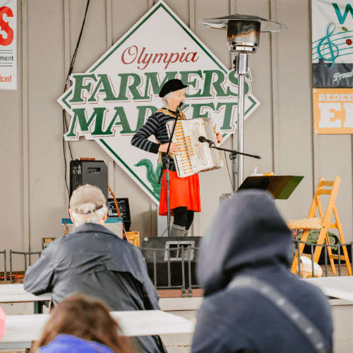 a man in a costume standing on a stage playing an accordion at Harbor Heights 55+ Community, Olympia, 98501