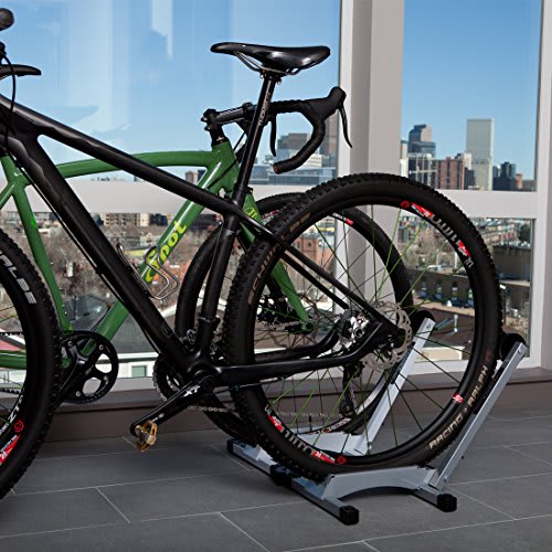 A black and green bike is leaning against a stand in front of a window.