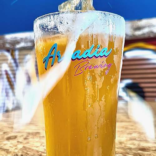 A glass of beer with the label "Aradia Brewing" on it.