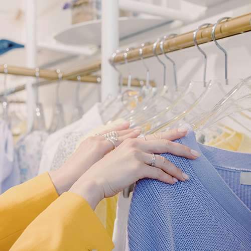 A woman is holding a blue skirt in a clothing store.