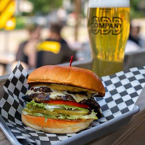 A burger and a glass of beer on a table.
