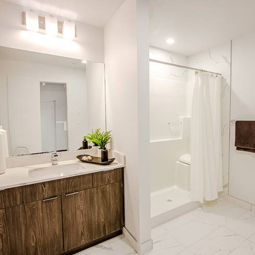 A bathroom with a white sink and brown cabinet.