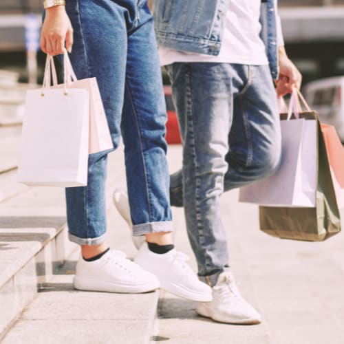 three people walking down the street holding shopping bags