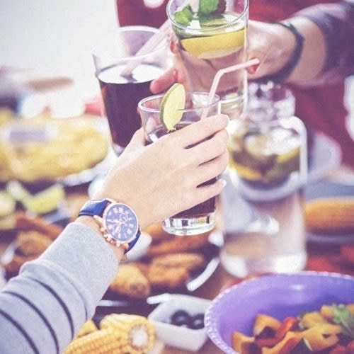 a group of people sitting at a table with drinks and food