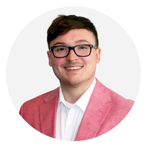 a young man wearing glasses and a pink suit