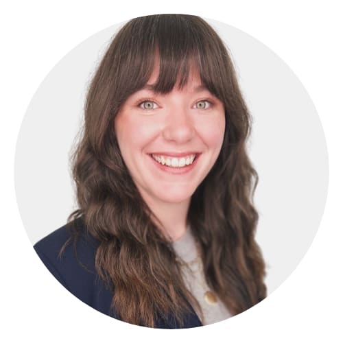 A woman with brown hair and bangs is smiling.