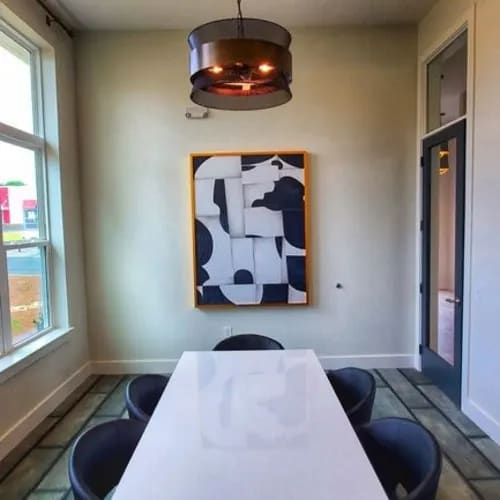A white table with a white cloth on it and a painting on the wall behind it.