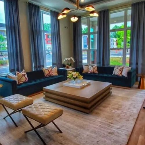 A living room with a blue couch, a coffee table, and a vase of flowers.