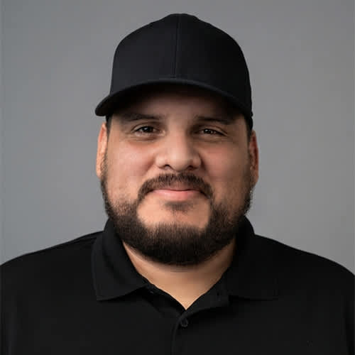 A man with a beard and a black cap is wearing a black shirt.
