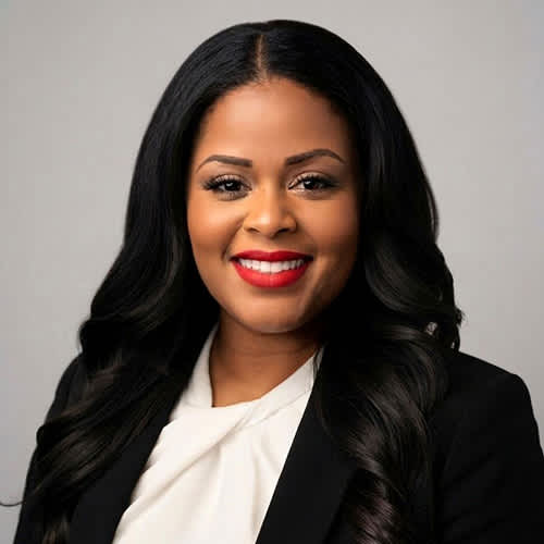 A woman with long black hair and red lipstick wearing a black blazer and white shirt.