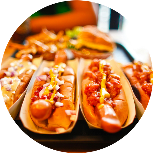 a row of hot dogs with chili and cheese on them