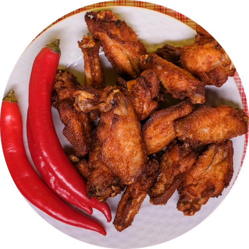 a plate of chicken wings and red peppers on a white plate