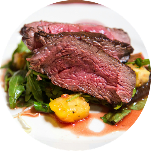 a plate of steak and vegetables with sauce on it