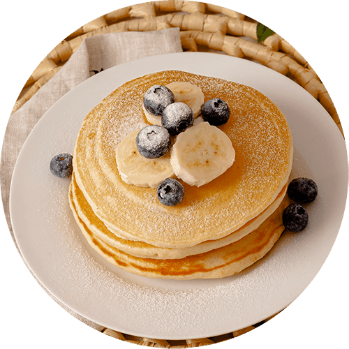 a stack of pancakes with banana and blueberries on a white plate
