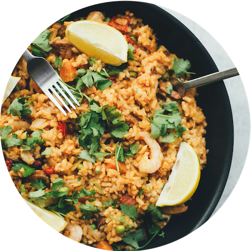 a plate of shrimp fried rice with a fork and a lemon wedge