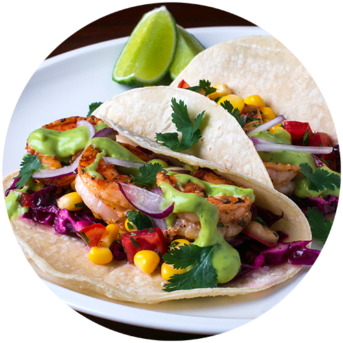 two tacos with shrimp and vegetables on a white plate