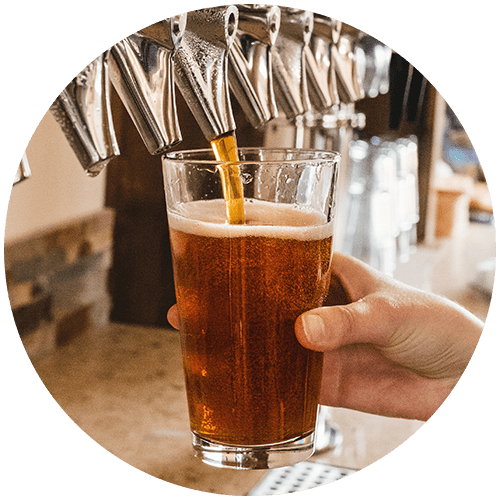a hand holding a glass of beer in a bar