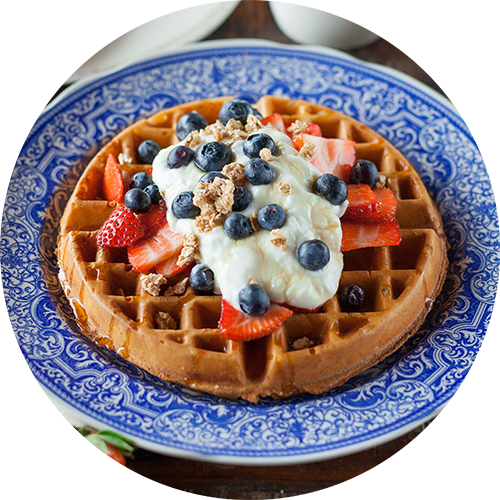 a waffle with whipped cream and berries on a plate