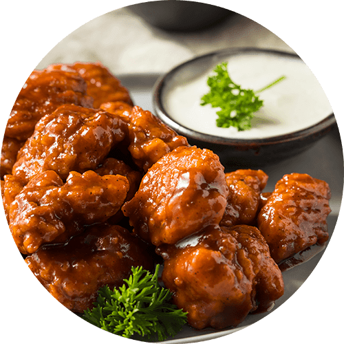 A plate of fried chicken wings and two red chili peppers.
