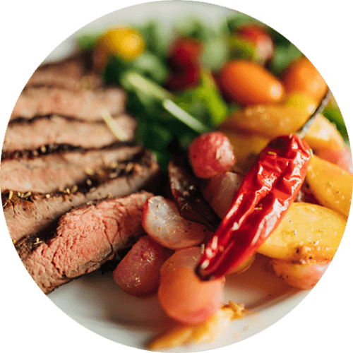 A plate of food with steak, potatoes, carrots, and a chili pepper.
