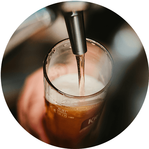 A close-up of a glass of beer being poured from a tap.