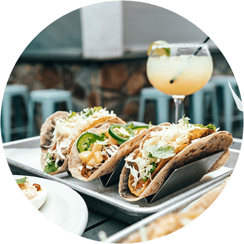 a plate of tacos and a cocktail on a table