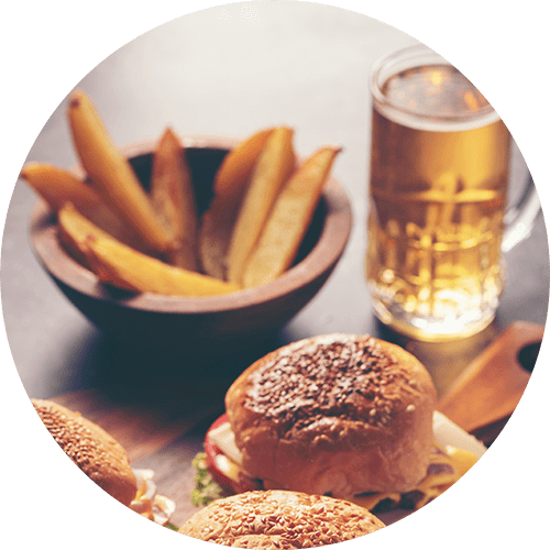 a table with a hamburger and fries and a glass of beer