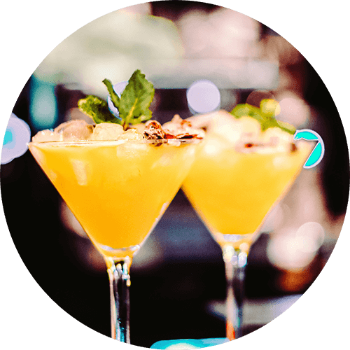 Two cocktails with a mint leaf garnish on top.