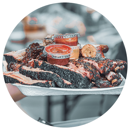 A plate of barbecued ribs with two sauces.