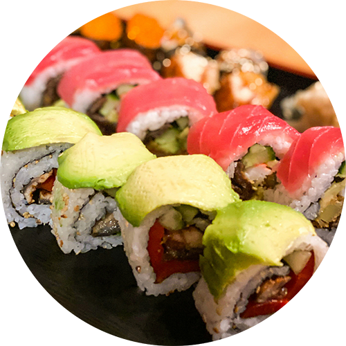 A close up of sushi rolls with pink and green toppings.