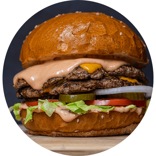 a large hamburger with cheese and toppings on a bun