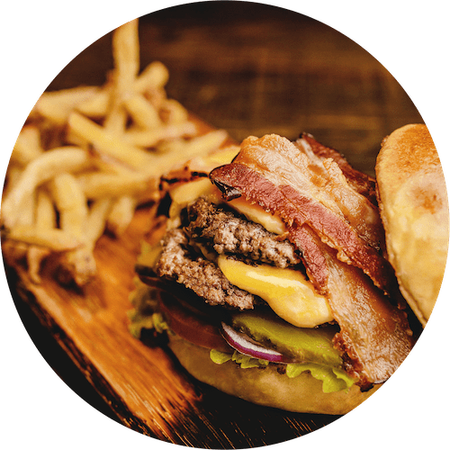a bacon cheeseburger and fries on a wooden plate