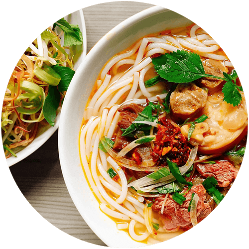 a bowl of noodles with meat and vegetables next to a plate of pasta