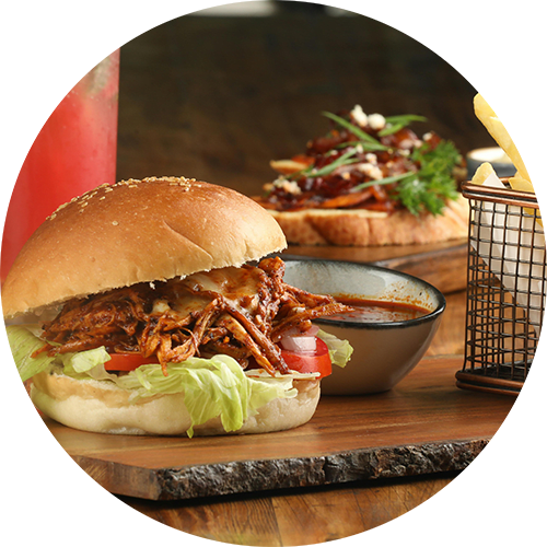 A pulled pork sandwich with a side of coleslaw and a drink.