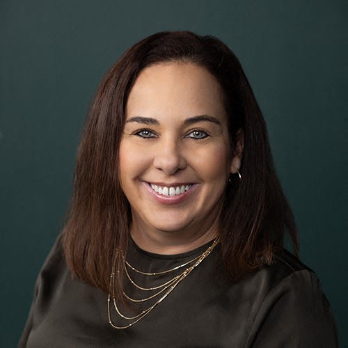 a woman wearing a black shirt and a necklace smiles at the camera