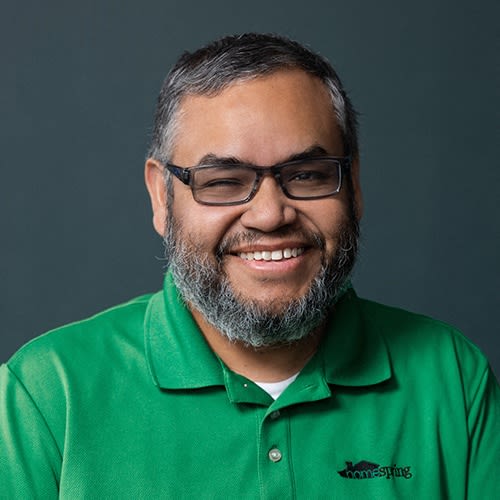 a man wearing glasses and a green shirt is smiling