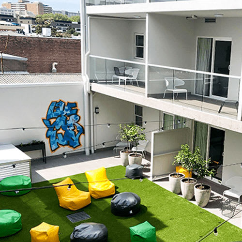 an open balcony with green turf and black and yellow chairs