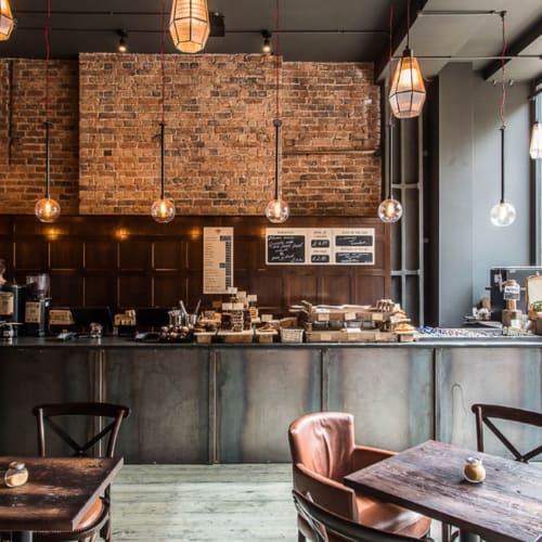 A coffee shop with a brick wall and wooden furniture.