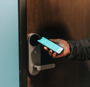 a hand holding a smart phone in front of a door