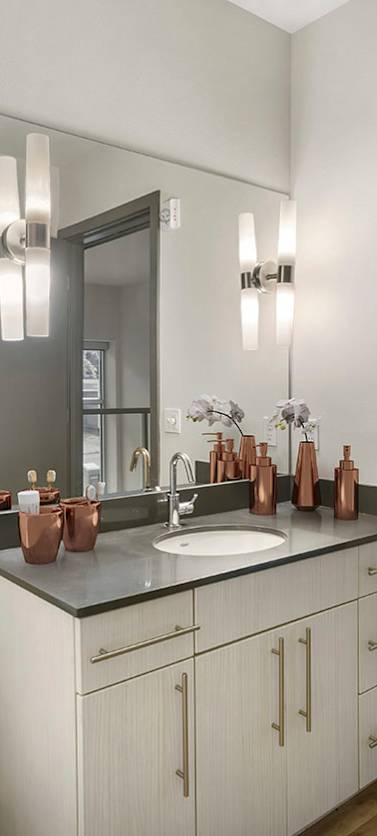 A bathroom with a sink, mirror, and copper vases.
