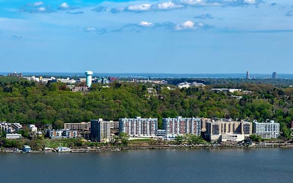 A cityscape with a large body of water in the foreground and a mix of residential and commercial buildings.
