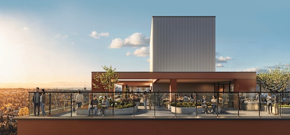 A modern building with a balcony overlooking a cityscape at sunset.