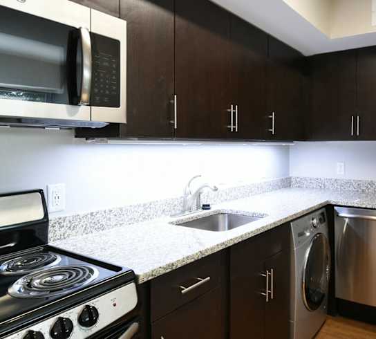 a kitchen with dark cabinets and stainless steel appliances