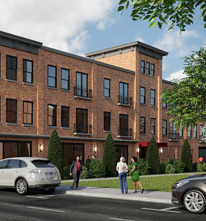 A street view of a red brick building with cars parked in front and people walking on the sidewalk.