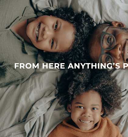a family lying on a bed with the words from here anything is possible
